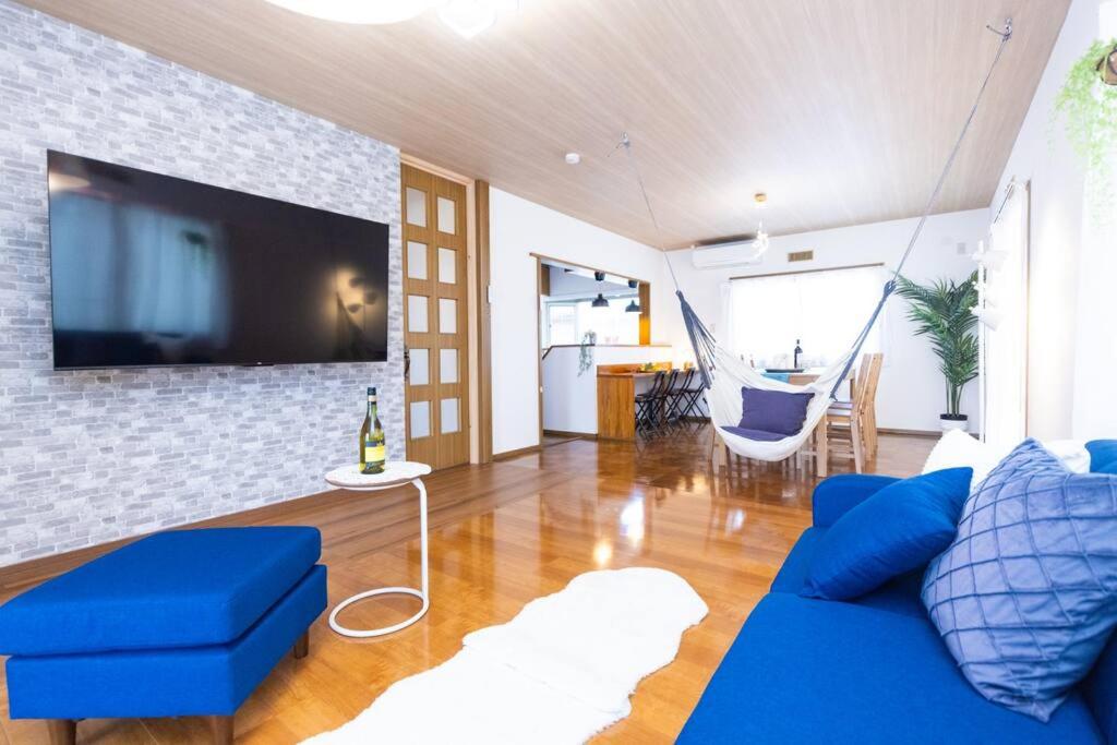 a living room with a blue couch and a tv at Shiga Lakeside House in Hamabun in Imazu