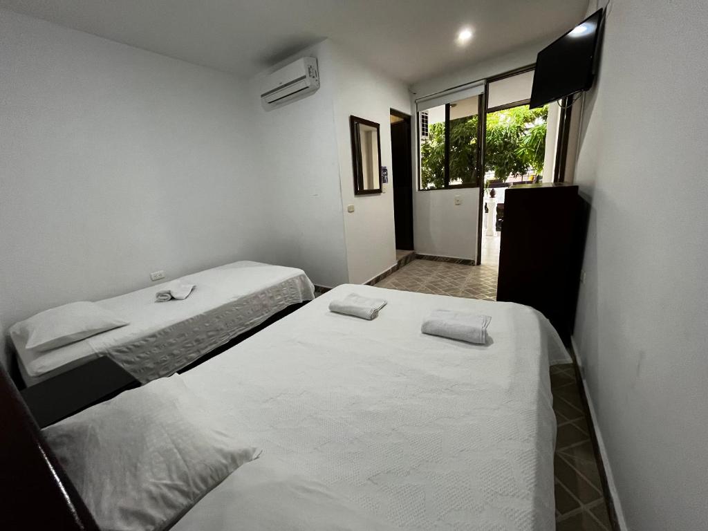 two beds in a small room with a window at Hotel Restaurante Versalles in Melgar