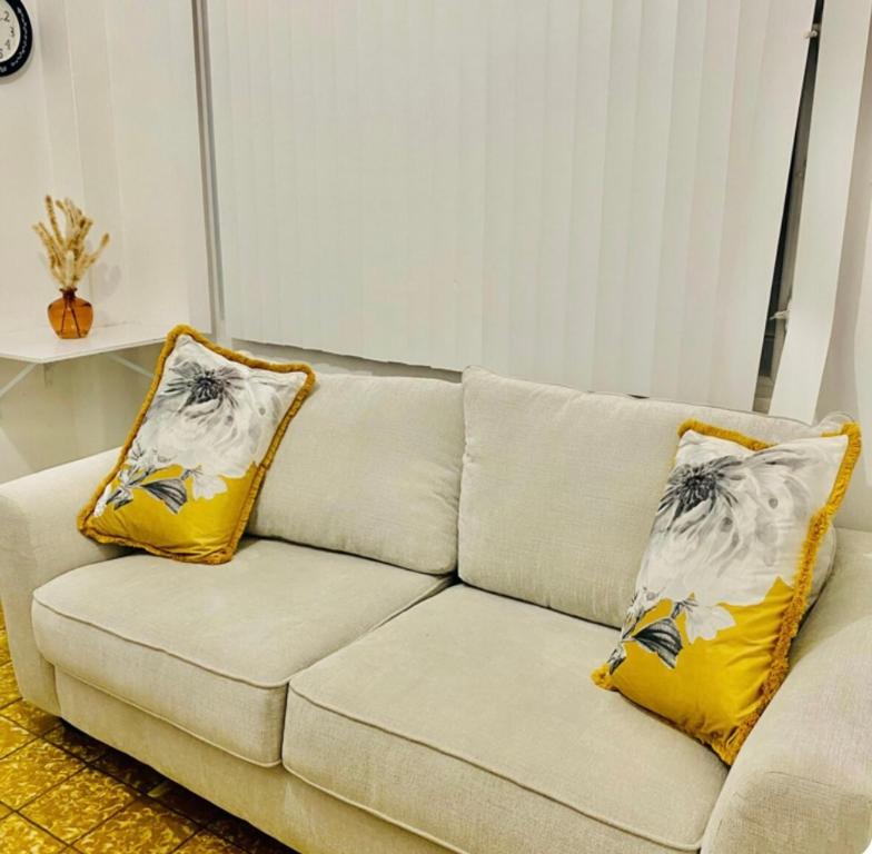 Un sofá blanco con dos almohadas amarillas. en FavoritePlace1BR 1 Btr 2 a/cs TV WF 1 PK -4 guests, en San Juan