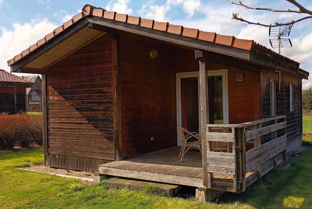 eine kleine Holzhütte mit einer Veranda und einem Stuhl in der Unterkunft Chalet 1 au coeur des volcans in Bromont-Lamothe