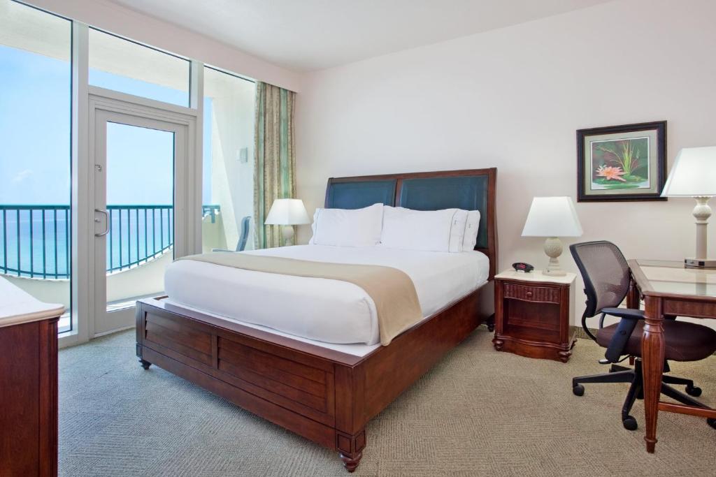 Holiday Inn Express Pensacola Beach, an IHG Hotel في شاطئ بينساكولا: غرفه فندقيه بسرير وشرفه