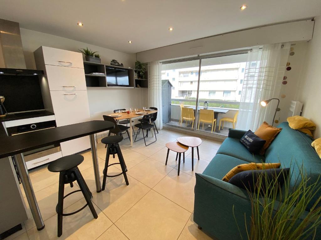 un salon avec un canapé bleu et une cuisine dans l'établissement Studio Cabine à Arcachon avec Parking, WiFi et Accès Direct Plage - FR-1-374-219, à Arcachon