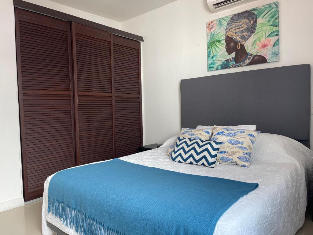 a bedroom with a bed with a blue comforter and pillows at Cerca a hotel las americas in Cartagena de Indias