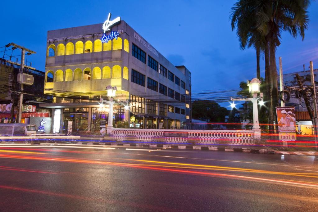 a building with a neon sign on the side of a street at Quip Bed & Breakfast in Phuket Town