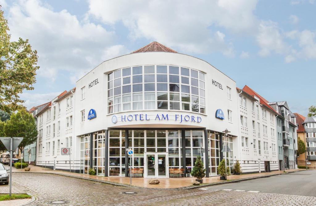 a large white building with the hotel an hoc at Hotel am Fjord in Flensburg