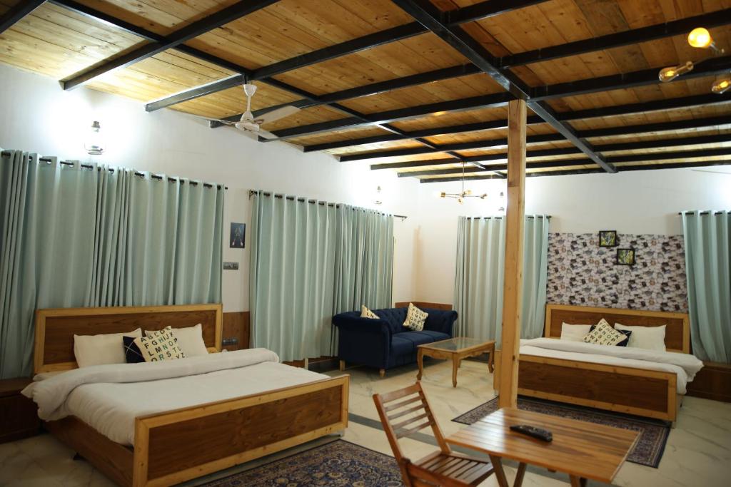 a bedroom with two beds and a couch and a table at Pinewood Nirvana Jungle Resort Shoghi in Shimla