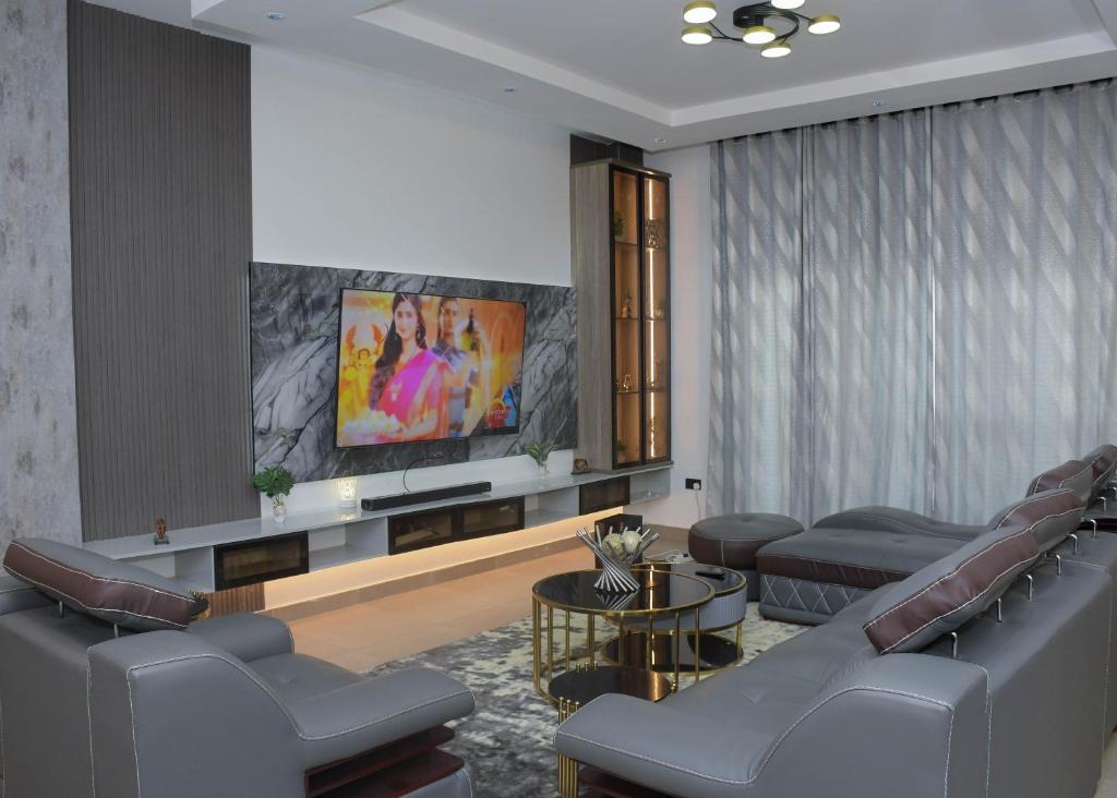 uma sala de espera com sofás e uma televisão de ecrã plano em Margi Homes em Apapa Eleko