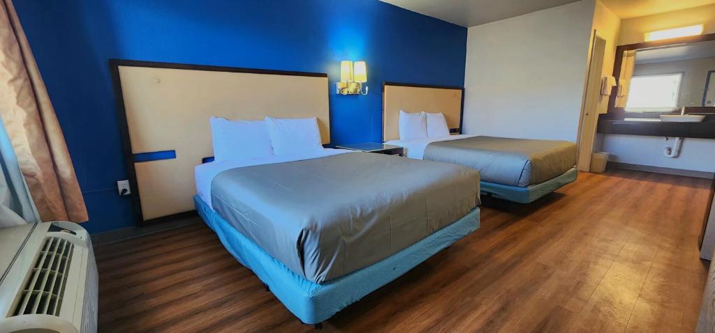 a hotel room with two beds and blue walls at Country Yard Inn and Suites in Sikeston