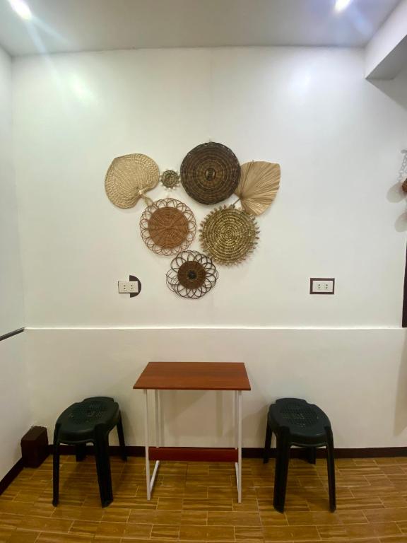 a table and two stools on a wall with hats at Moalboal Panagsama beach TopBudz Hostel in Moalboal