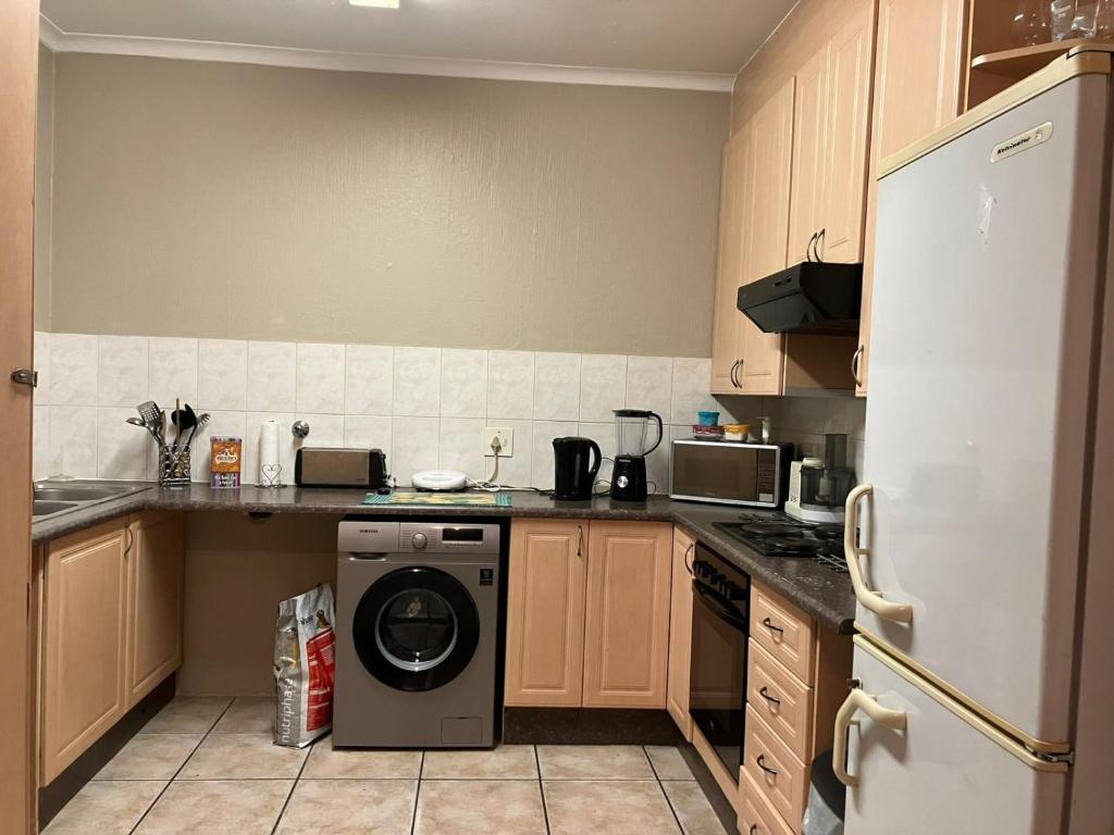 a kitchen with a washer and a refrigerator at Secure Townhouse Bedroom Immediately Available in Roodepoort