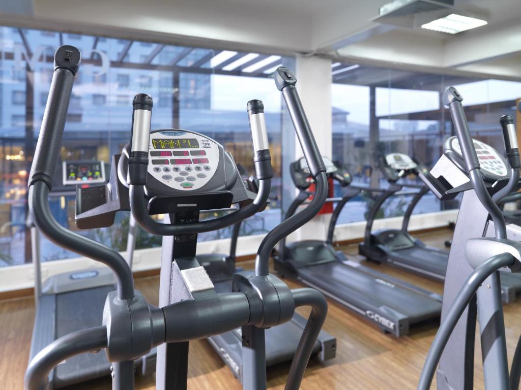 A bright fitness room with treadmills and cross-trainers beside large windows.