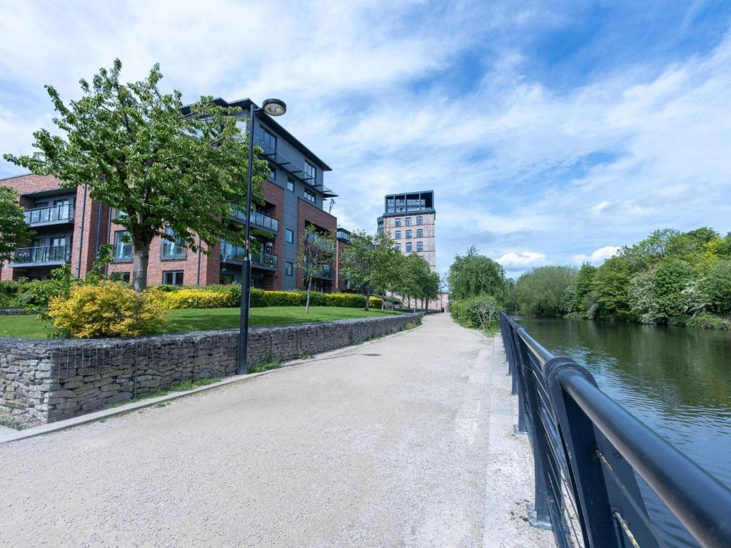 a walkway next to a river next to buildings at Leeds Haven Niche 1 2 Bedroom Apartments with Cityscape views by Sojo Stay in Leeds