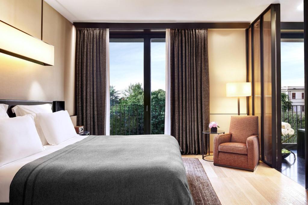 a bedroom with a bed and a chair and a window at Bulgari Hotel Milano in Milan