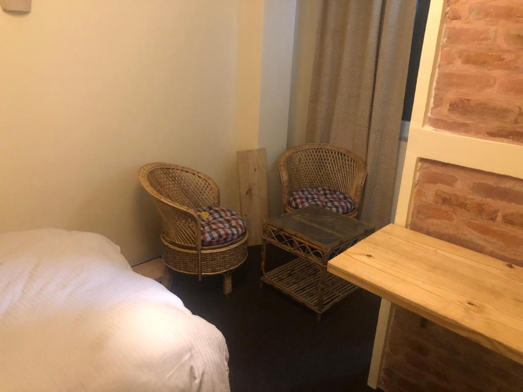sypialnia z 2 krzesłami, łóżkiem i stołem w obiekcie Newari homestay w mieście Patan