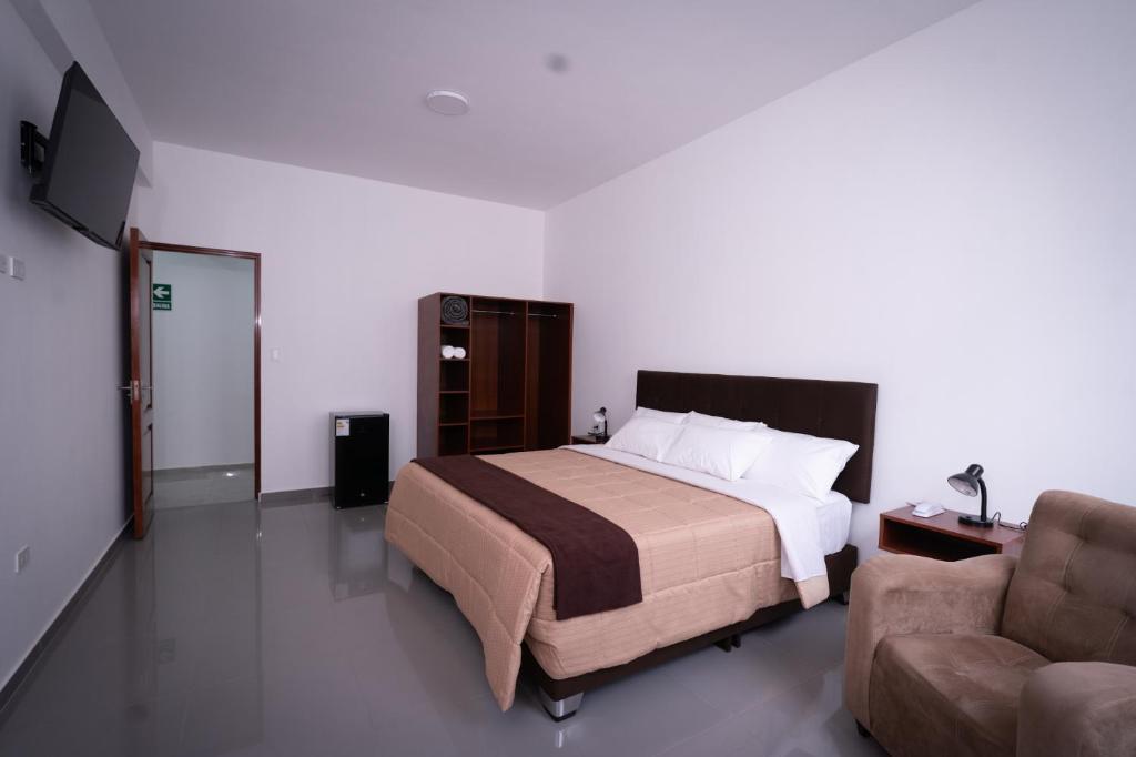 タクナにあるBruan Hotelのベッドルーム1室(ベッド1台、椅子、ソファ付)