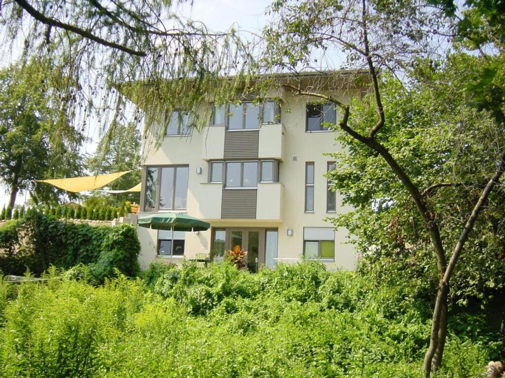un grand bâtiment jaune avec des arbres devant lui dans l'établissement Villa am Weinberg Waren, à Waren