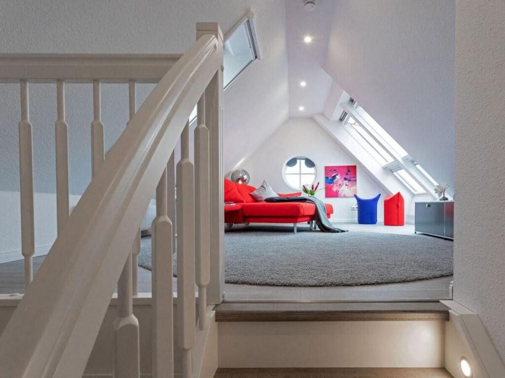 uma sala de estar com um sofá vermelho e escadas em Wild Duck Modern Retreat em Greetsiel