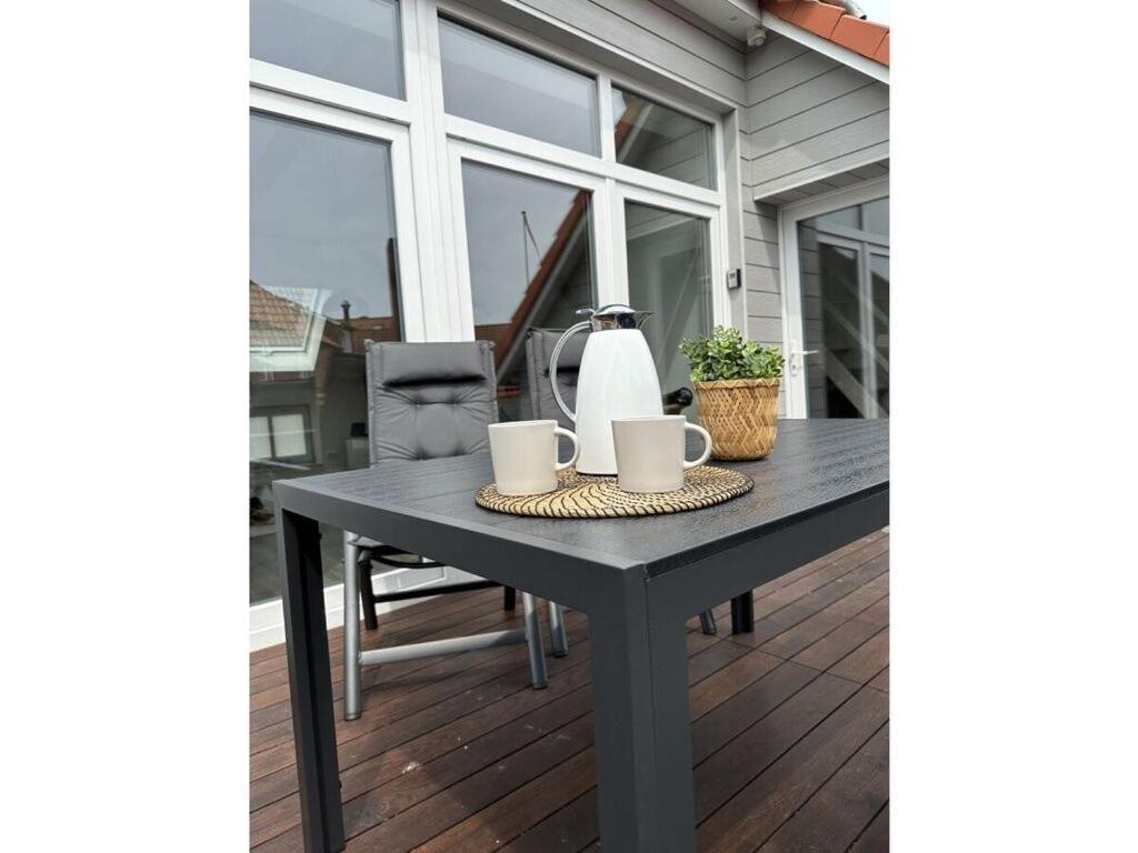 uma mesa preta num alpendre com duas chávenas em Fischerstuv Modern retreat em Tönning