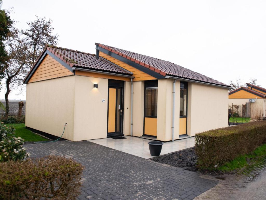 une petite maison blanche avec une allée. dans l'établissement Wellness Bungalow with whirlpool and sauna, à Zevenhuizen