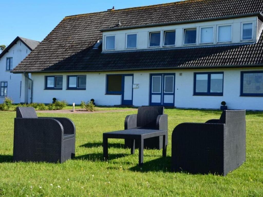 a group of chairs sitting in the grass in front of a house at Langeneß Modern retreat in Steenodde