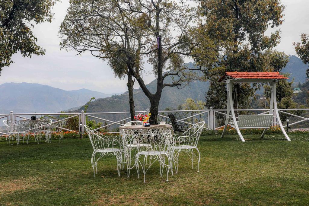 a table and chairs in a field with a tree at The Mountain Quail in Mussoorie