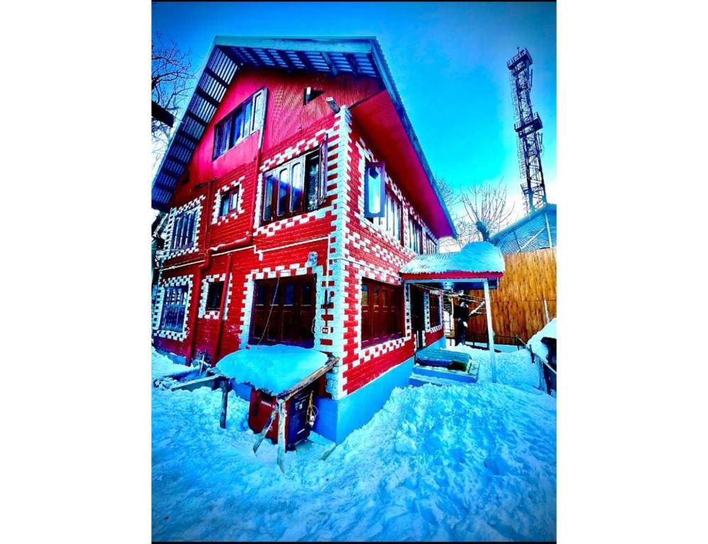 a red building with snow on it in the yard at Hotel Dayban Resort, Pahalgam in Pahalgām