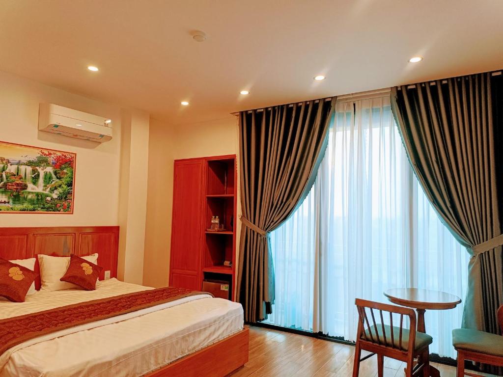 1 dormitorio con cama, mesa y ventana en PHƯƠNG ĐÔNG HUẾ HOMESTAY en Hue