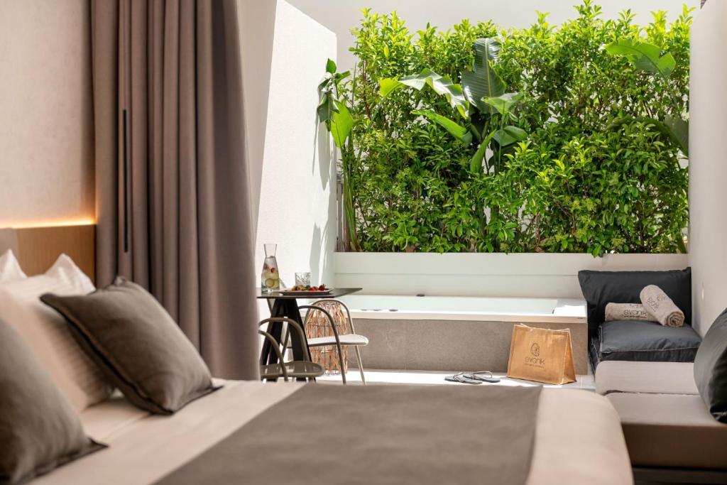 een slaapkamer met een bed en een grote groene heg bij Evanik Chic Hotel in Kalymnos