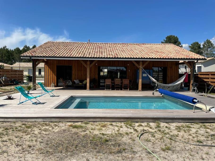 une maison avec une piscine et un hamac ainsi qu'une maison dans l'établissement Maison typique proche bassin Arcachon, à Salles