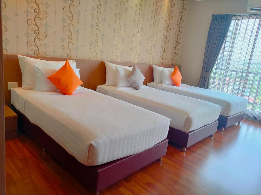 2 camas con almohadas de color naranja en una habitación en Tonaoi Grand Hotel en Hat Yai