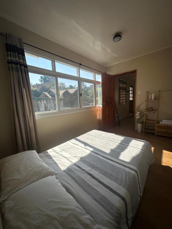 a bedroom with a large bed with a large window at Riverside 2bed cozy apartment in La Trinidad