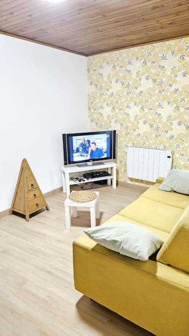 - une chambre avec un lit jaune et une télévision dans l'établissement Maison berrichonne 4 pers, à Niherne