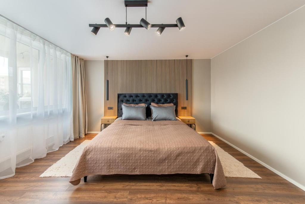 a bedroom with a large bed with blue pillows at Stiklo Apartamentai in Radviliškis