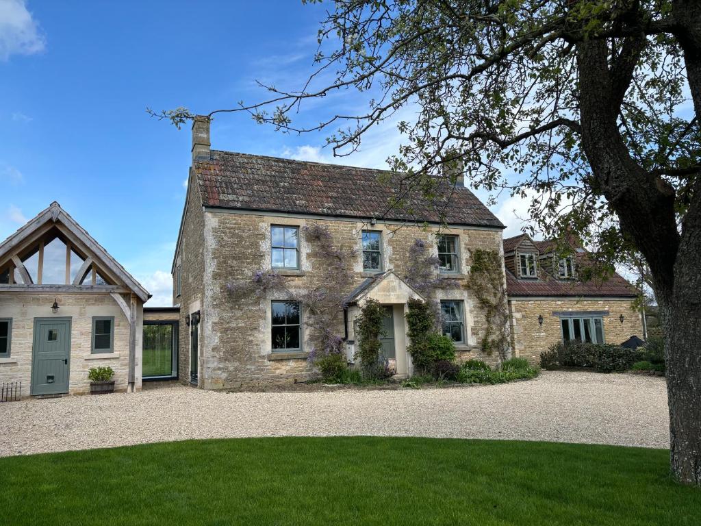 una vieja casa de piedra con un árbol delante en Stylish Secluded Country Retreat with Garden, en Whitley