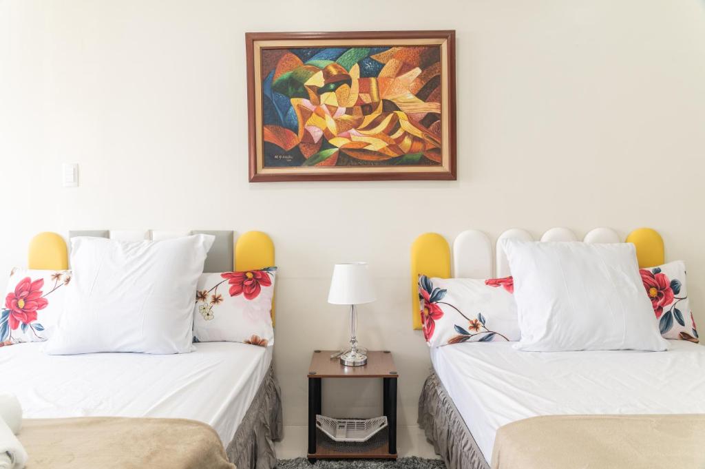 two beds in a room with a painting on the wall at Wind Residence 4 in Tagaytay