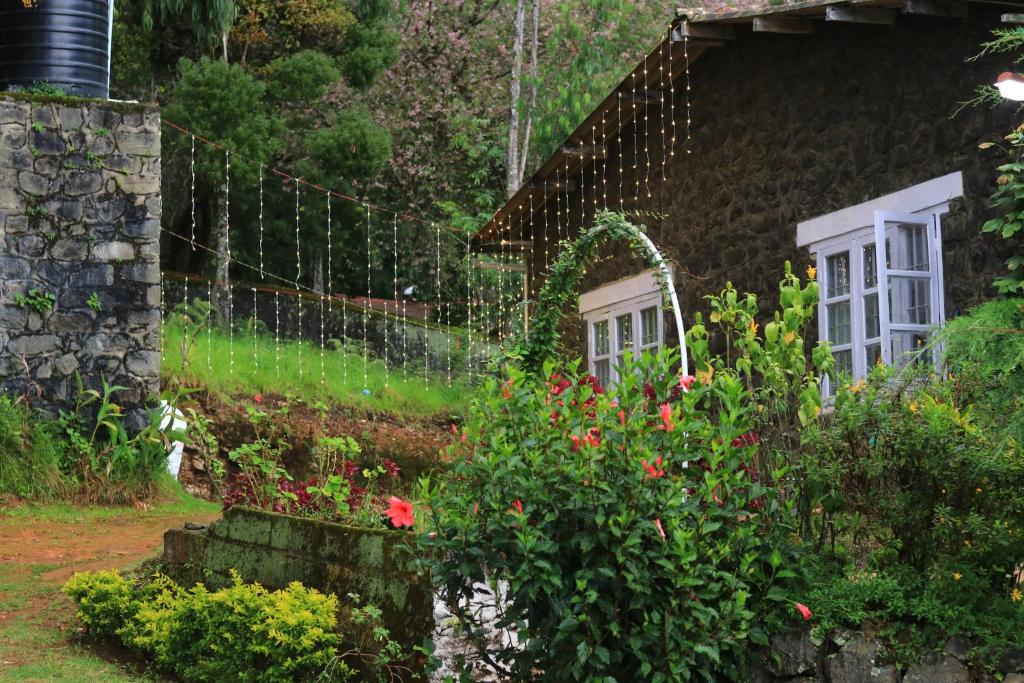 a garden with a house with a fence and flowers at De Huts Kodaikanal in Kodaikānāl