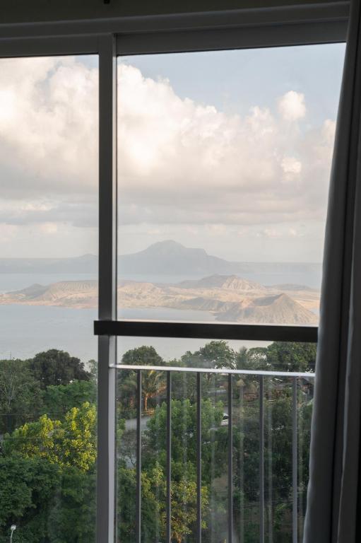 a window with a view of the mountains and water at Taal View or LG Unit 1BR Wifi Near Sky Ranch in Tagaytay