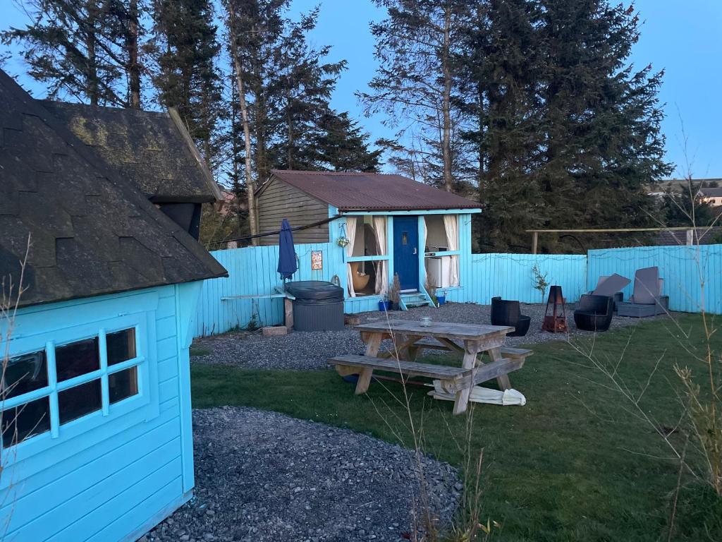 a backyard with a picnic table and a blue fence at Bankhead Accommodation with Hot Tub Aberdeenshire in Gamrie