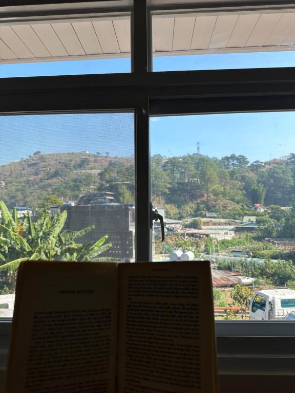a book in front of a window with a view at Riverside 2bed cozy apartment in La Trinidad