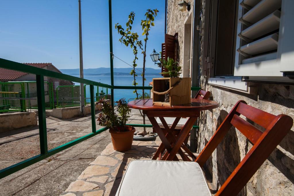 een tafel en stoel op een balkon met uitzicht op het water bij Old Town Accommodation in Bol