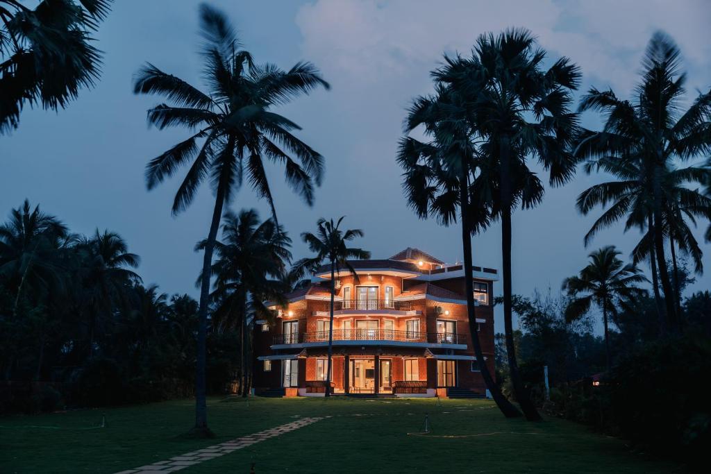 una casa grande con palmeras delante en Tatasth Beach Villa, en Kundapur