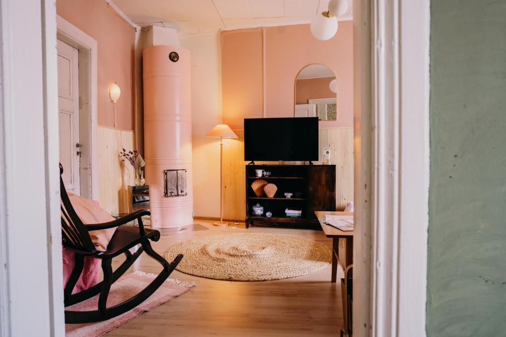 een woonkamer met een stoel en een flatscreen-tv bij Idyllinen huvikumpu Vanhan Rauman ytimessä, In the heart of Old Rauma in Rauma