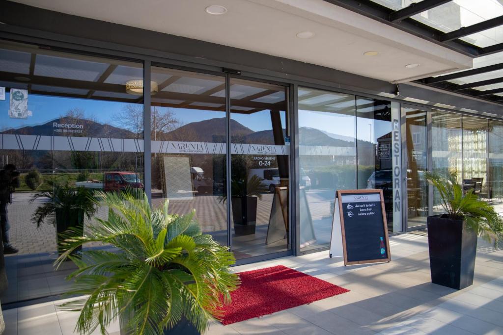 une façade de magasin avec des fenêtres en verre et un tapis rouge dans l'établissement Hotel Narenta, à Metković