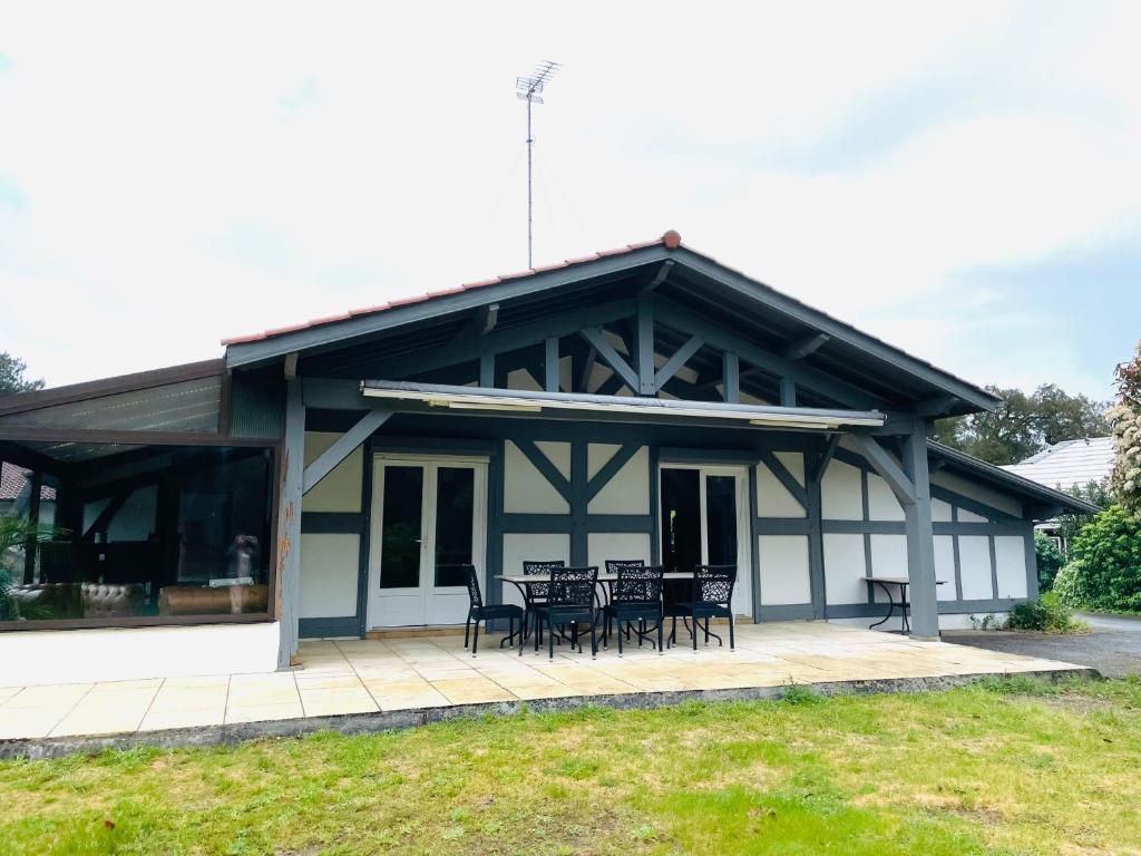 a house with chairs and tables on a patio at Chalet entre océan et foret au calme in Ondres