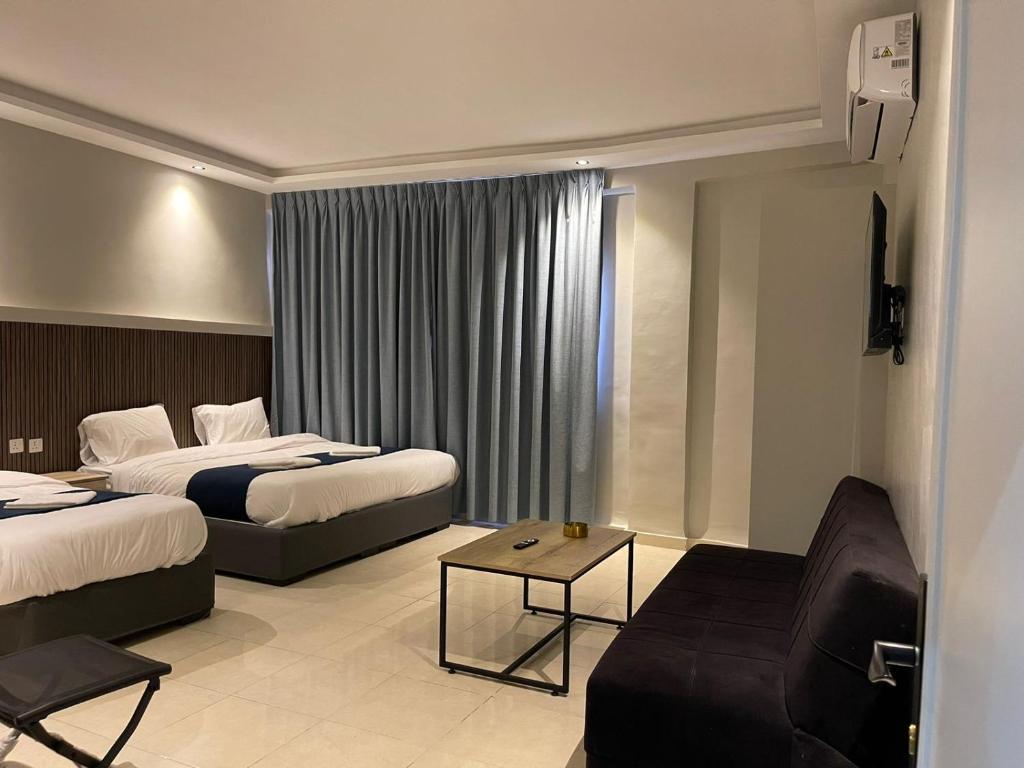 アカバにあるAladnan hotelのベッド2台とソファが備わるホテルルームです。