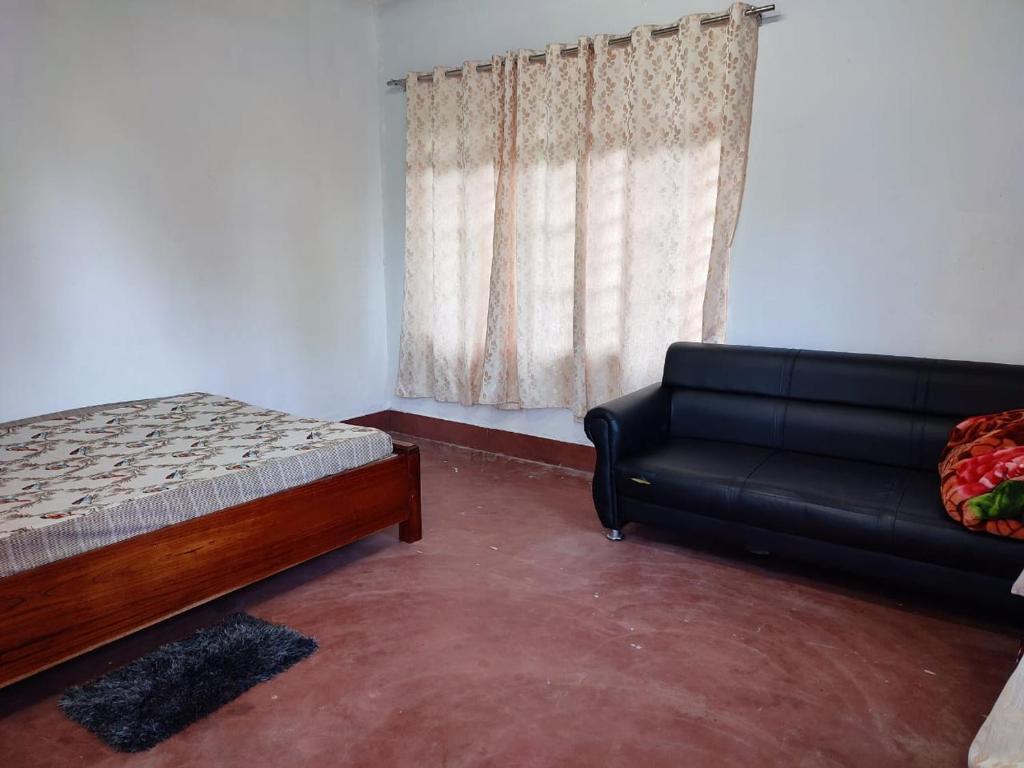 a bedroom with a bed and a couch and a window at Keyie Homestay, Mima in Kohīma