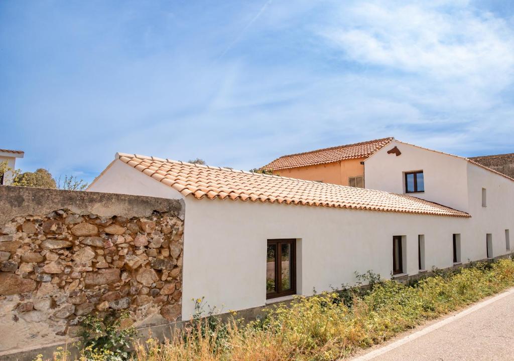 a white house with a stone wall at Casa Feraxi at Casa Sardinia in Muravera