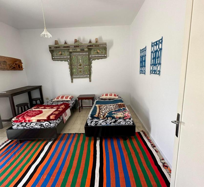 2 Betten in einem Zimmer mit farbenfrohem Teppich in der Unterkunft Anis 2 in Sousse