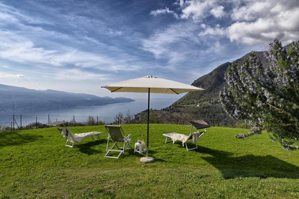 two chairs and an umbrella on top of a field at Appartamento Orizzonte - Rebomaholidays in Tignale