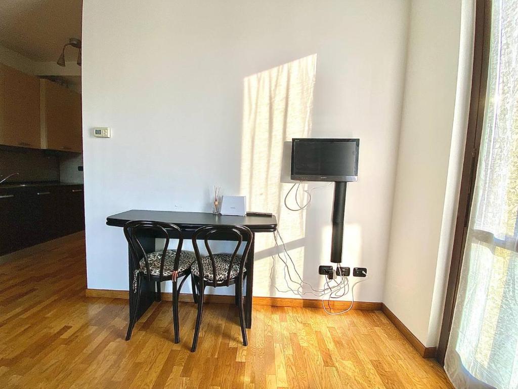 mesa negra con 2 sillas y TV en una habitación en Graziosa in coorte tranquilla con parcheggio gratuito riservato, en Cologno Monzese